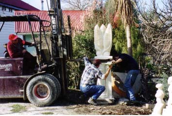 People and a forklift assembling the two pieces of a stone sculpture